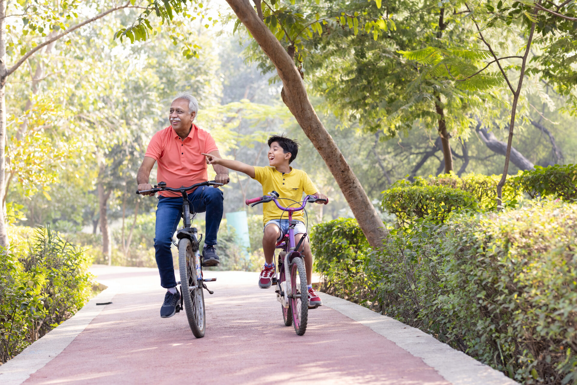 Happy grandfather and grandson riding bicycle at park