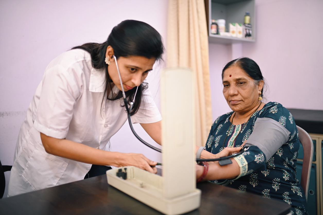 Female doctor examining blood pressure of a senior woman patient